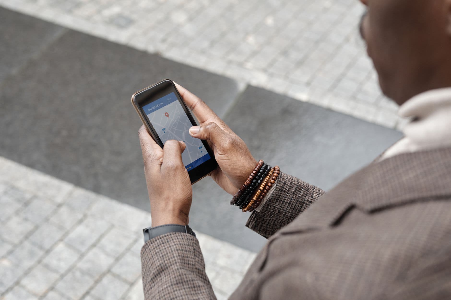 Sokakta telefonundaki harita uygulamasına bakan kişi